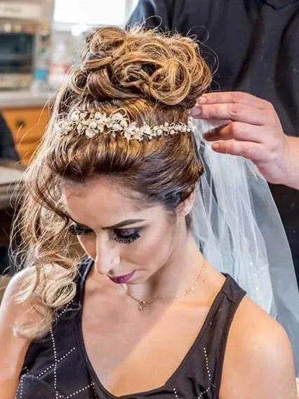 High curled bun held by a pearl band, with the veil going in