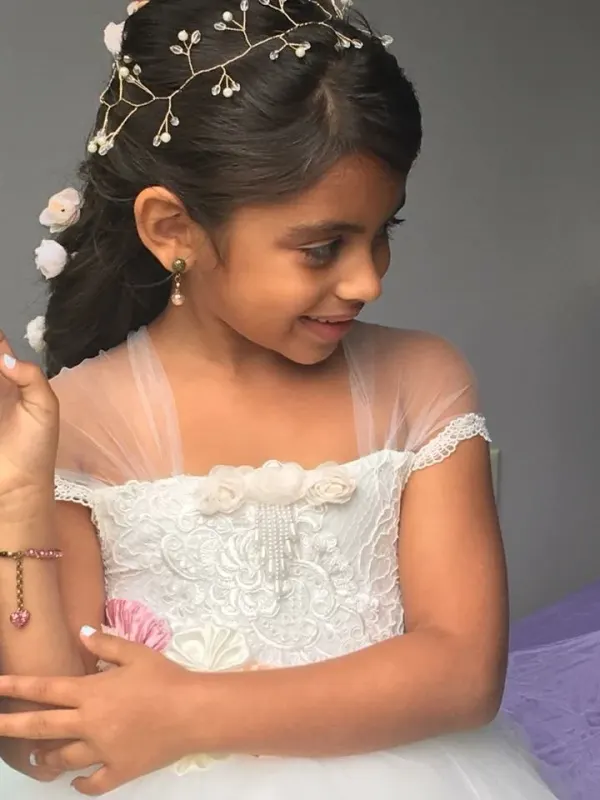 Flower girl hair worn half up and dressed with a pearl and flower vine