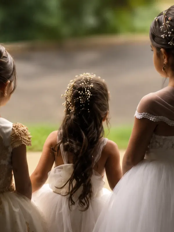 Flower girls from the back, each with her own updo dressed with flowers
