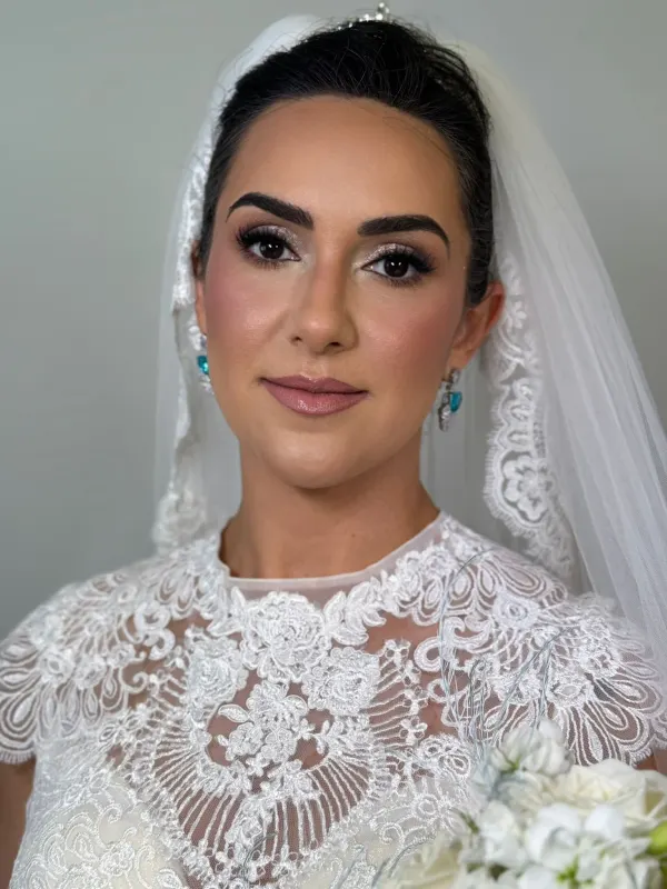 Bridal hair pulled back clean under a lace veil, set to hold all day